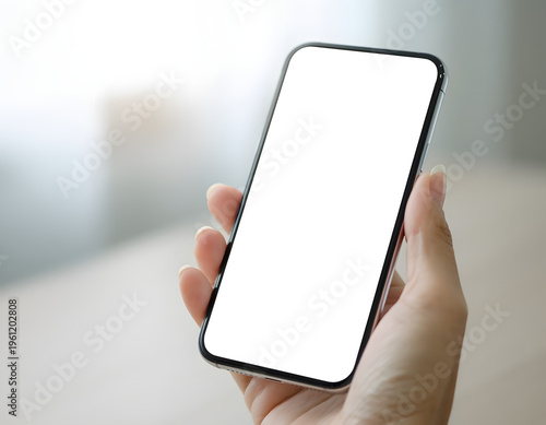 手に持ったスマートフォンの白画面モックアップ、アプリデザインや広告バナー用のコピースペース素材