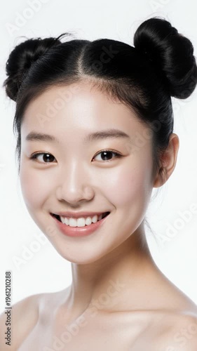 Young asian woman with playful double buns hairstyle smiling gently