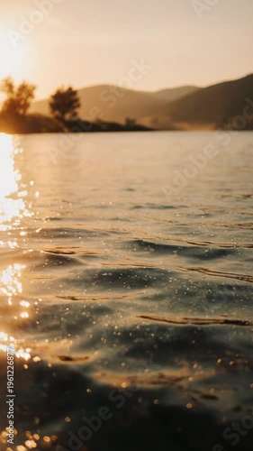 Serene lake water with sunset reflection on ripples, mountains in background, peaceful natural scenery for relaxation