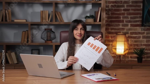 Business woman completes document and shares it with a smile in a modern office space.