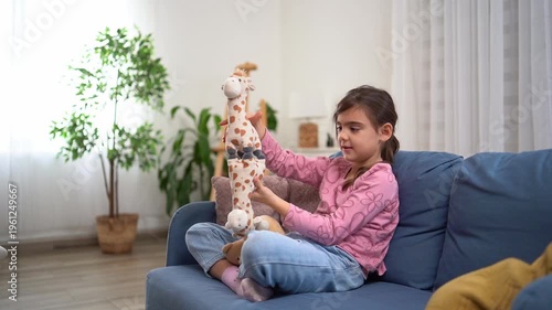 Focused young girl concentrating while trying to balance plush toys
