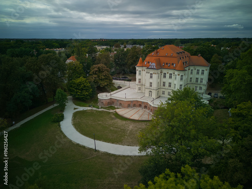Aerial view of Lesnica Castle in Wroclaw, Poland on an overcast day. Baroque palace with moat and surrounding parkland under cloudy sky.