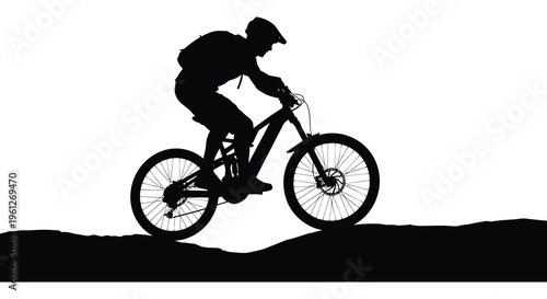 Mountain biker riding uphill against a bright background silhouette
