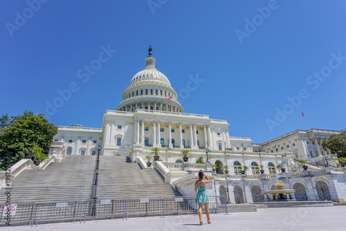 Woman smiles near Capitol's grand steps under bright sun