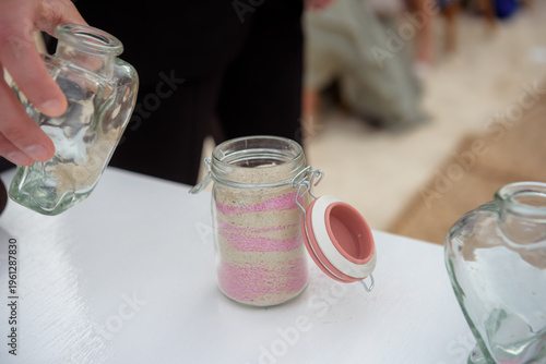 Hands pouring sand into jar during wedding unity ritual