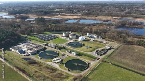 Diepenbeek, Belgium. Aerial drone footage of wastewater treatment facility with circular basins and solar panels in rural landscape