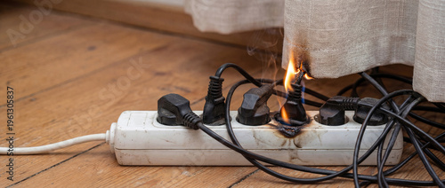 Curtain catching fire from burning overloaded electric power strip with tangled cords. Common home fire hazard scenario