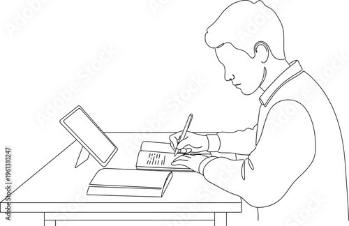 Focused young student diligently taking notes in a physical book while referencing digital resources on a nearby standup tablet device