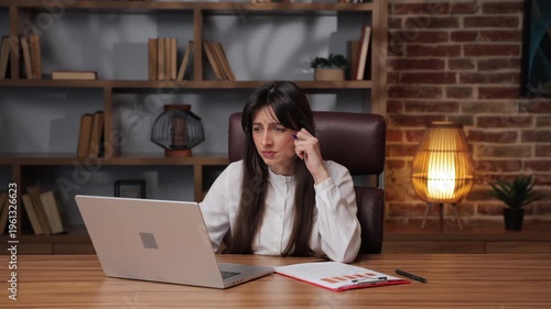 Caucasian business woman shows alarm while working at desk in modern office.