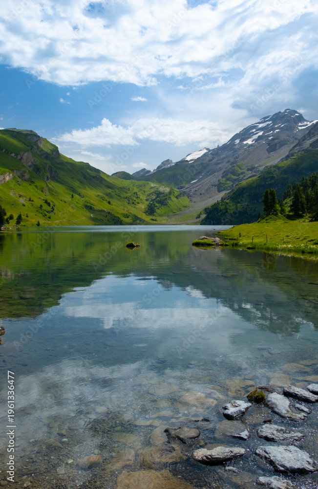 Fototapeta premium Discover the beauty of Engstlensee Lake in Switzerland. Clear waters reflect surrounding mountains and greenery, showcasing a serene natural landscape. Travel destination and popular trail.