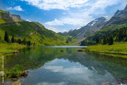 Discover the beauty of Engstlensee Lake in Switzerland. Clear waters reflect surrounding mountains and greenery, showcasing a serene natural landscape. Travel destination and popular trail.