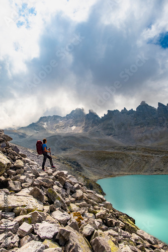 Female hiker with backpack enjoying epic view of Wildsee lake on Pizol mountain range in Switzerland. Travel sport wanderlust concept.