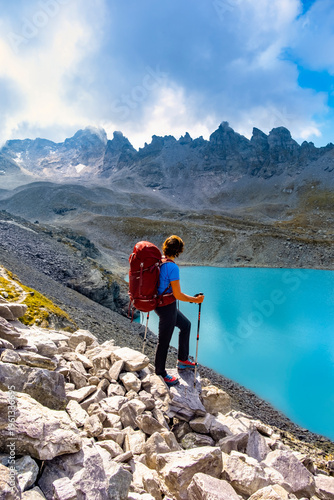 Female hiker with backpack enjoying epic view of Wildsee lake on Pizol mountain range in Switzerland. Travel sport wanderlust concept.