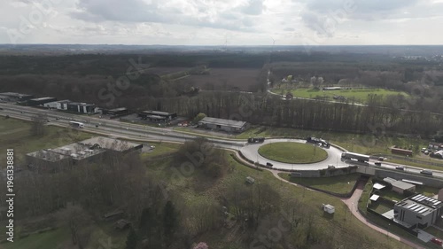 Genk, Belgium. Aerial drone footage of roundabout with traffic and suburban landscape under cloudy sky