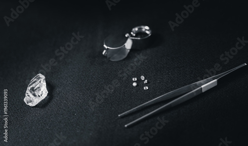 Konstfotografi Loose diamonds and tweezers arranged on dark textured surface, top view