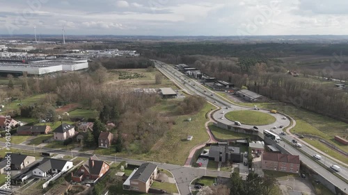 Genk, Belgium. Aerial drone movement revealing suburban neighborhood transitioning into industrial zone with wind turbines