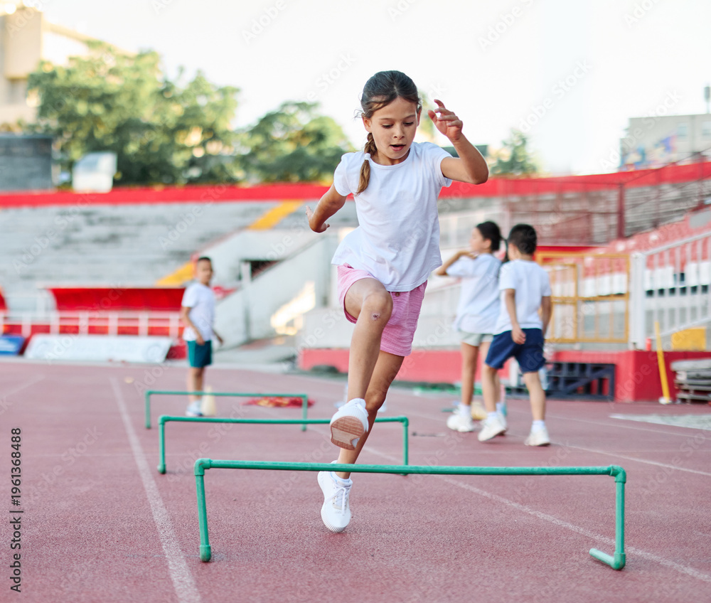 Obraz premium Children running on track at the stadium, practice during sports class in school training with their coach teacher, little fit boys and girls in sportswear training as athletes outdoor. Concept of sp