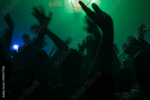Silhouetted Crowd at Concert with Raised Hands and Stage Lighting