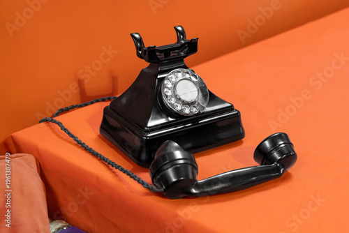 Tableau sur toile Vintage rotary telephone on orange table with bold background