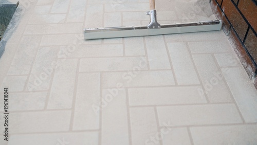 фотографія Spreading polymeric sand into joints of new outdoor herringbone paver patio