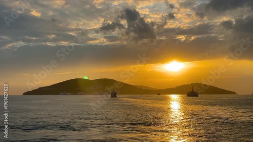 Passenger ferries crossing the sea at sunset with a flying seagull and silhouette of the Princes Islands in Istanbul, golden reflection on water and dramatic evening sky