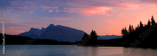 Sunset over Jack Lake and Rocky Mountains with trees visible along the shoreline near Banff, Alberta, Canada