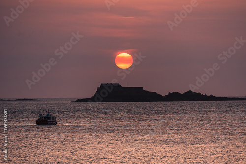 Golden-red sky at dusk over English Channel with Fort National and small boats in Saint Malo, France