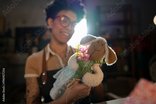 Fotografie A woman smiles as she holds a doll made of fabric, adorned with flowers
