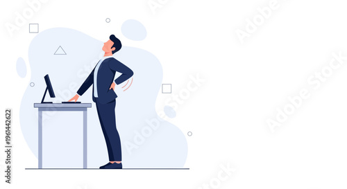 Businessman suffering from back pain while standing at his desk with computer