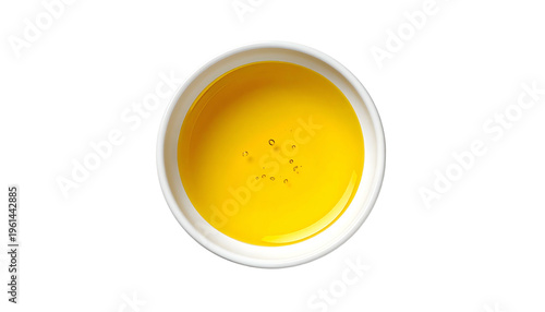 Top-down shot of a small white bowl filled with golden-yellow liquid, on black