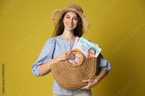 Woman with lifestyle magazines and bag on olive background