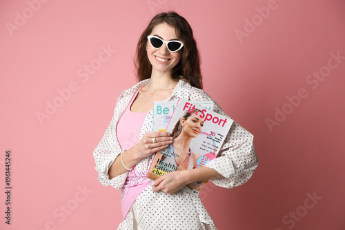 Woman with lifestyle magazines on pink background