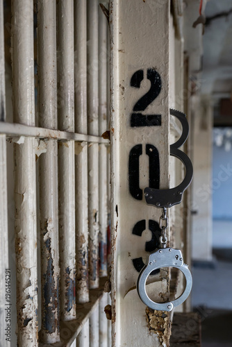Closeup of  a pair of hand cuffs hanging on cell door in prison.