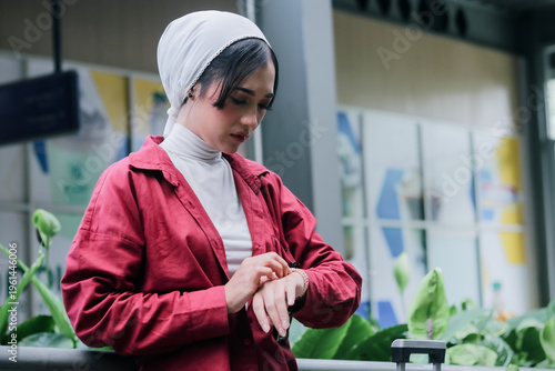 A sophisticated muslim woman in hijab is checking her wristwatch, a symbol of her valuing time in a hectic daily life. This shows a modern islamic lifestyle and elegance.