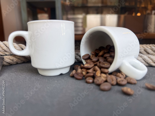 Quadro em tela coffee beans spilling from white espresso cup on dark surface, concept of cafe,