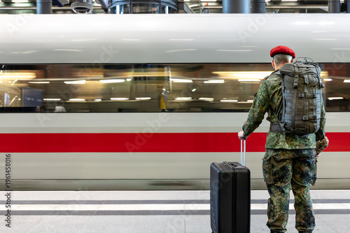 Soldier with backpack and suitcase waiting on platform. Travel transport concept.
