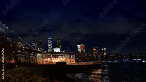 New York, USA, 2 August 2025: Illuminated Janes Carousel and Manhattan skyline at night. Glass pavilion of carousel on DUMBO waterfront with Brooklyn Bridge and city lights in background.