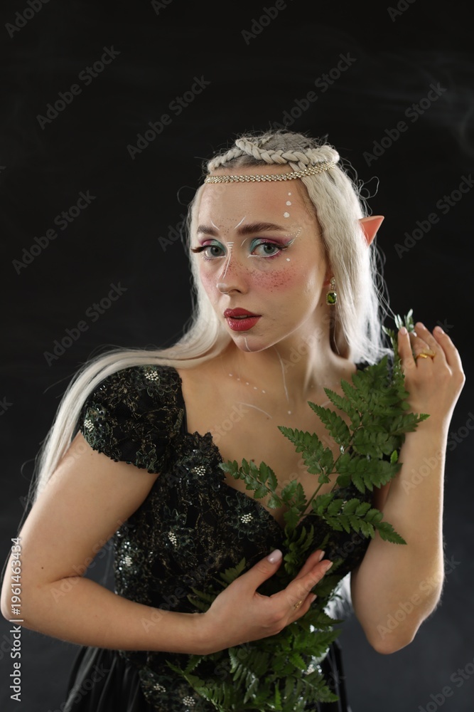 Obraz premium Beautiful elf girl with floral decor on black background with smoke