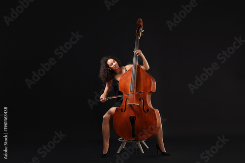 Foto Woman playing double bass on black background