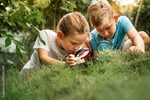 Foto Curious children exploring nature forrest with magnifying glass in garden, kids