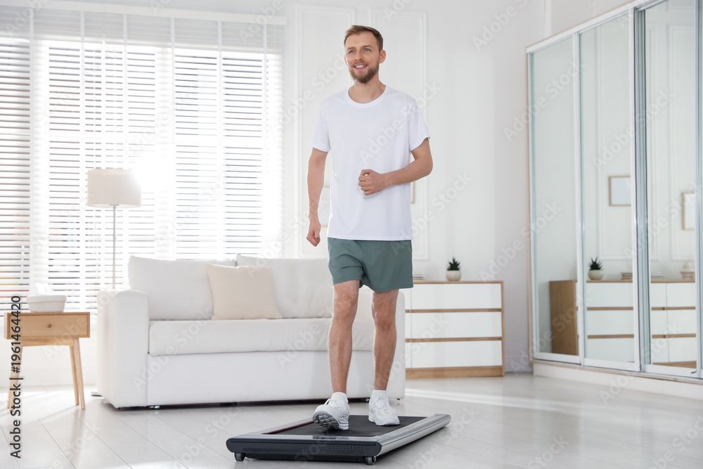 Fototapeta premium Sporty man training on treadmill at home