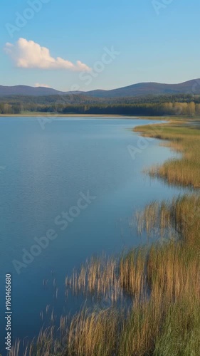 Serene lake shore with calm water and mountains in background