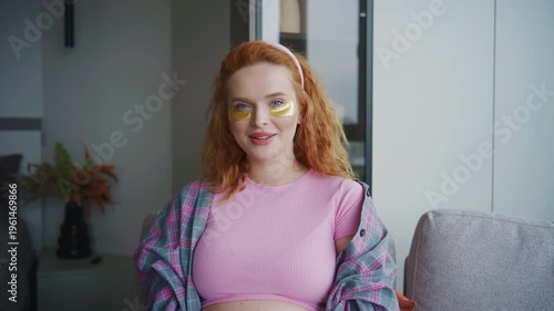 Young Pregnant woman smiles in a living room while wearing a pink top and yellow face stickers in the morning light