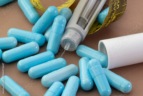 Close-up shot of blue medical capsules, a yellow measuring tape, and an injection pen on a neutral background, highlighting the connection between medication, weight loss, and health care