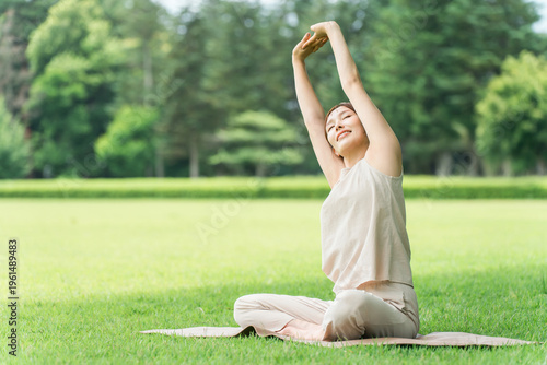 Young Asian women doing park yoga, yoga, Pilates, and stretching in a forest/park.