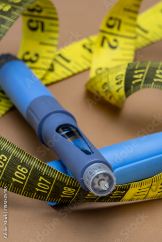 Blue medical injection pen with a needle tip lying on a brown surface surrounded by a yellow measuring tape, representing diabetes management and modern weight loss medical treatments