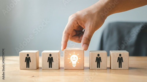 Wallpaper Mural Hand selecting a wooden block with a glowing light bulb and happy face icon from a row of people icons. Torontodigital.ca