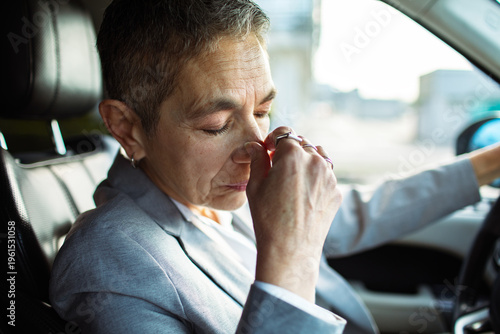 Stressed businessperson pinching nose bridge in car