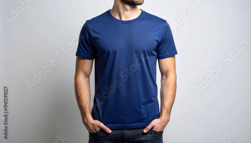 Front view of a fit man in a plain navy blue crew neck t-shirt and jeans. Clean studio shot against a neutral gray background perfect for apparel design mockups