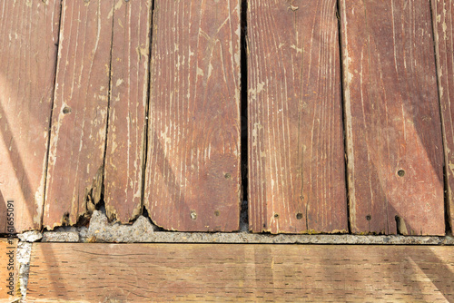 Wooden Planks Show Signs of Wear and Damage on a Sunny Day in a Rustic Outdoor Setting With a Background of Stone